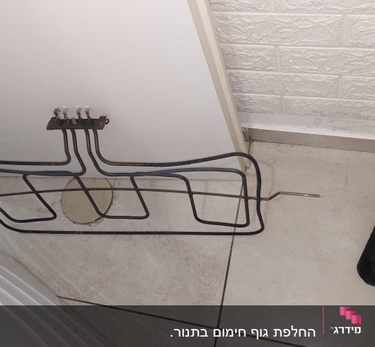 גוף חימום מתכת מונח על רצפה ליד תיק כלים